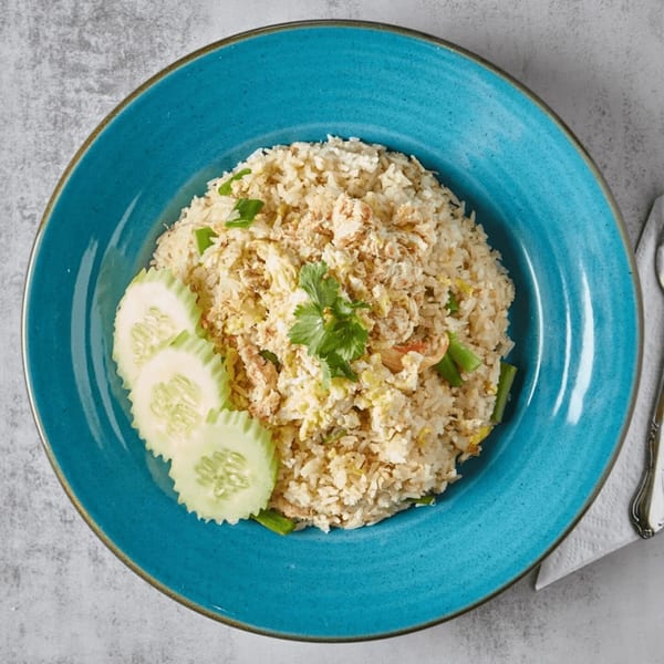 Crab fried rice with cucumber slices and cilantro on a blue plate.